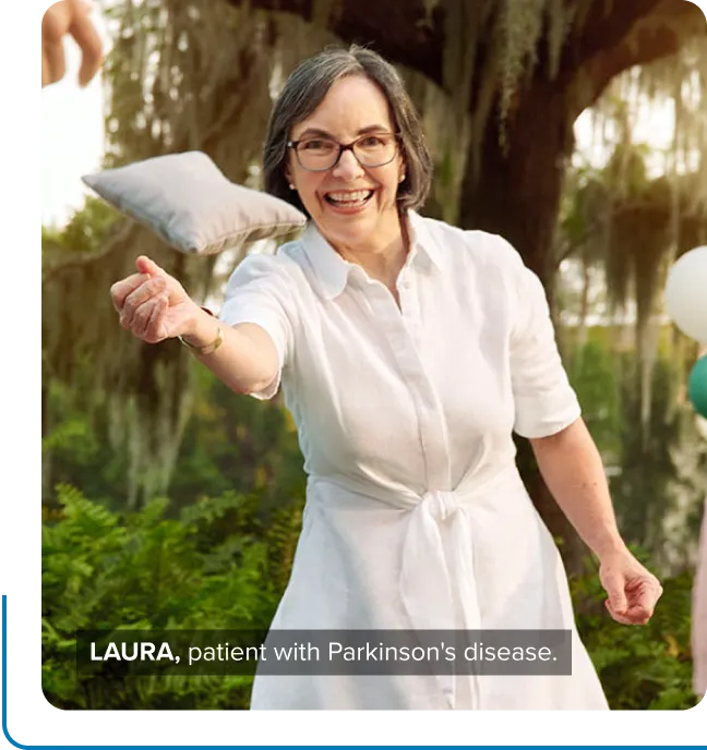 Laura, a patient with Parkinson’s disease, smiling and tossing a bean bag