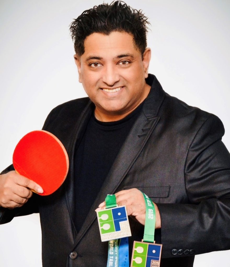 Image of Navin, a real patient taking CREXONT, holding a ping-pong paddle and his ping-pong medals.